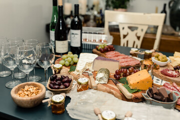 Wine glasses and bottles with charcuterie board featuring cheeses, nuts, and olives