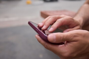 Close-up of a man hands using a phone, He plays a game using mobile internet. Turns the phone vertically. Red light in the evening room