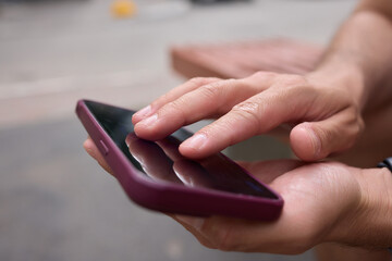 Close-up of a man hands using a phone, He plays a game using mobile internet. Turns the phone vertically. Red light in the evening room