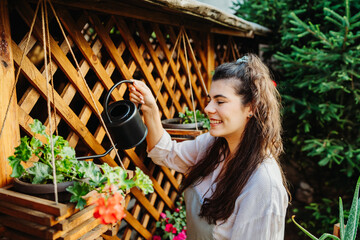 One young caucasian woman is taking care of her plants using plant mister and water can	