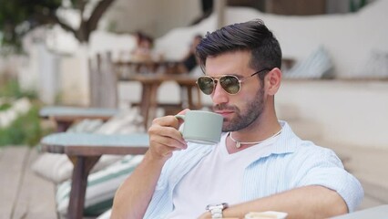 Happy Caucasian man enjoy outdoor lifestyle travel tropical island on summer beach holiday vacation. Handsome guy relaxing and drinking coffee at beach cafe and looking beautiful nature of the sea. - Powered by Adobe