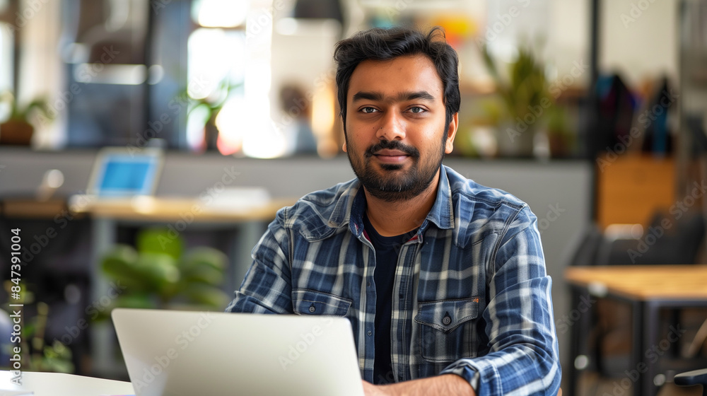 Poster portrait of an indian software engineer or web developer working on laptop in modern office looking 