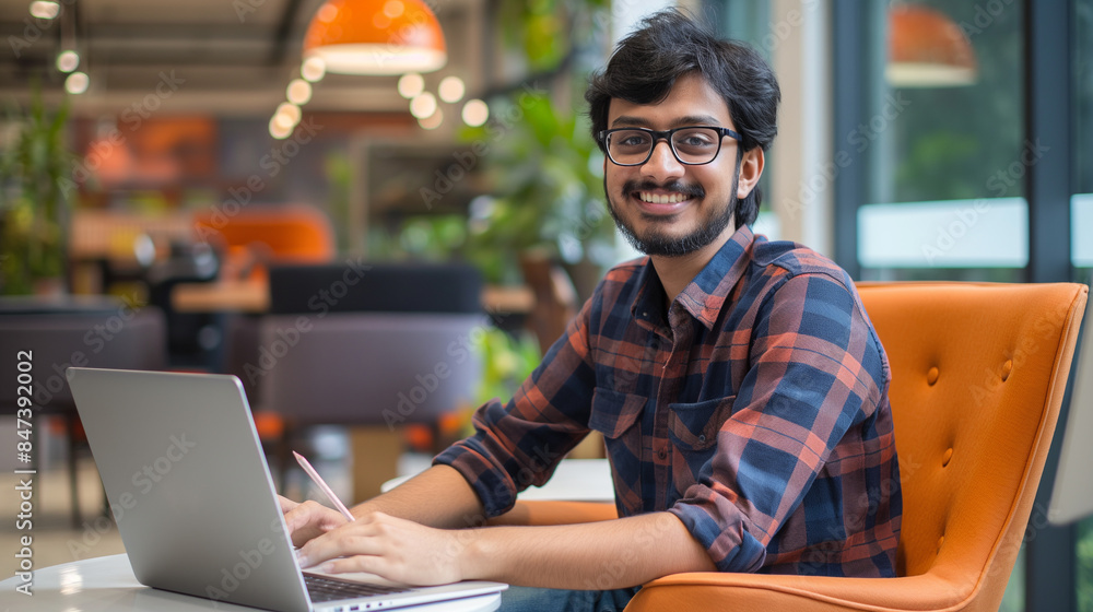 Poster portrait of an indian software engineer or web developer working on laptop in modern office looking 