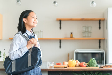 家のキッチンにいる制服を着た小学生・中学生・高校生の女の子
