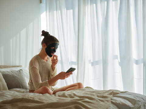 Woman with a face mask relaxing on a bed