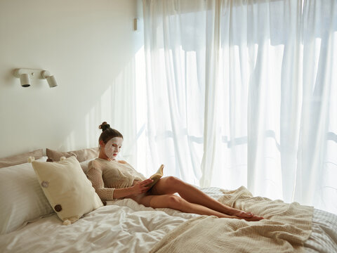 Woman in a face mask reading a book in ber
