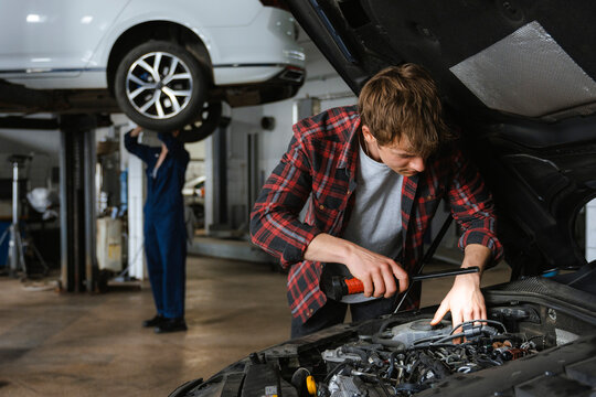 A man repairs a car in the garage