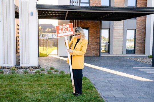A woman removes the "for sale" sign