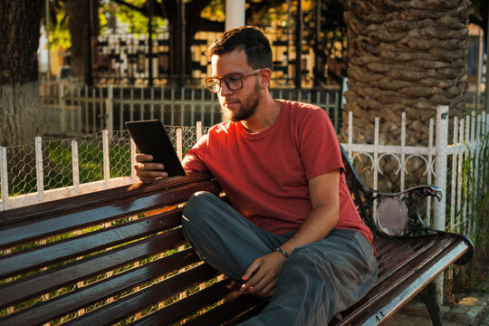 Man reading an e-reader on Park bench
