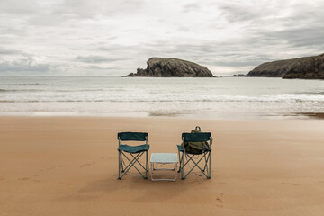 landscape of an idyllic beach with two empty chairs on the shore