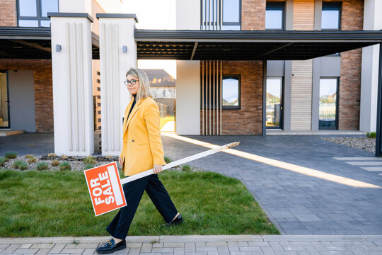 A woman removes the "for sale" sign