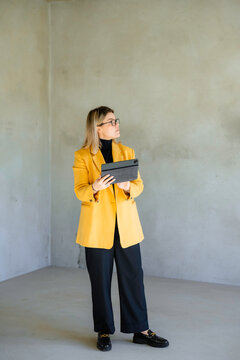 The real estate agent uses a tablet standing at the building