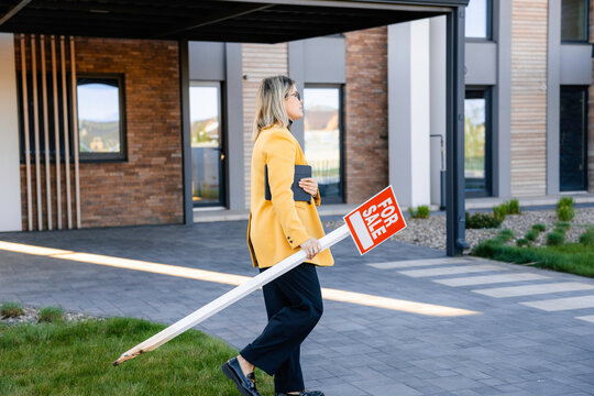 A woman removes the "for sale" sign