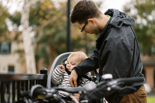 father putting infant son into bike carrier