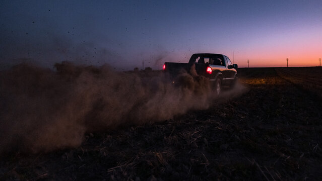 Pickup truck a cloud of dust from  the rear wheels.