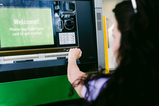 young woman getting cash at drive through ATM
