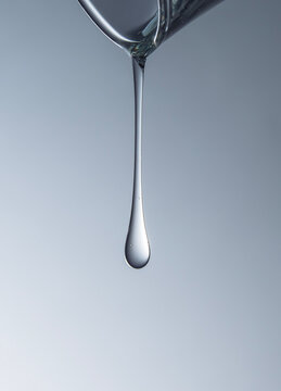 Close-up of face serum droplet against gradient blue background. 