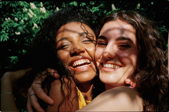 Film portrait of two friends hugging under the shade of trees