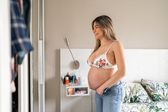 Pregnant woman having fun trying clothes.