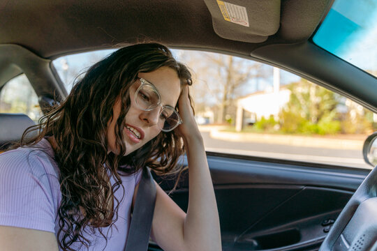 young woman with glasses  waiting in her car 