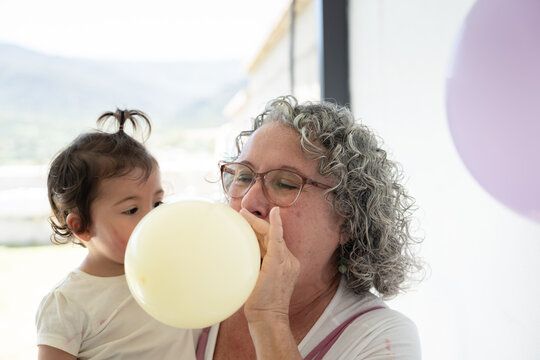 Grandmother and grandchild blowing balloons