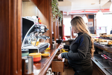 Pregnant barista at work in cafe