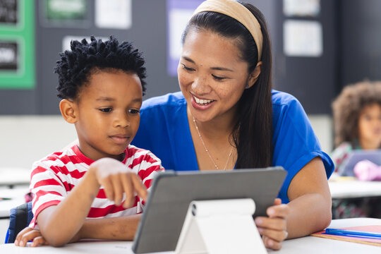 Biracial teacher showing African American student something on tablet