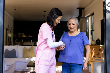 Asian nurse helps senior Asian woman with physical therapy exercises at home