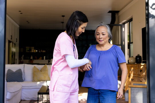 Asian nurse helps senior Asian woman with physical therapy exercises at home