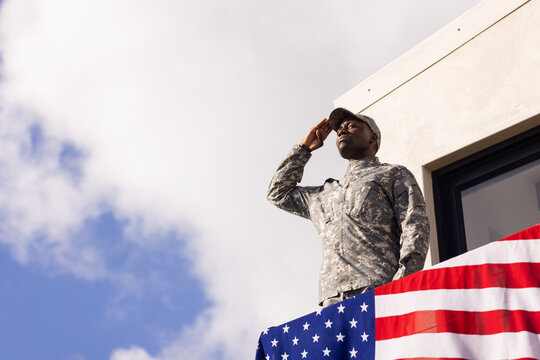 African American young soldier in military uniform saluting on balcony