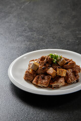 traditional chinese wok fried fat meat pork ribs chicken in spicy pepper and sweet sauce in plate on stone table hotel cafe luxury halal food restaurant banquet menu