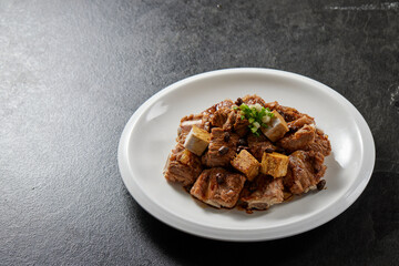 traditional chinese wok fried fat meat pork ribs chicken in spicy pepper and sweet sauce in plate on stone table hotel cafe luxury halal food restaurant banquet menu