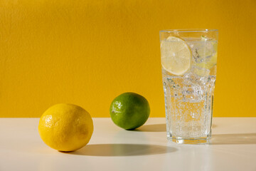Glass ice lemonade on yellow background. Minimal style composition summer drink.