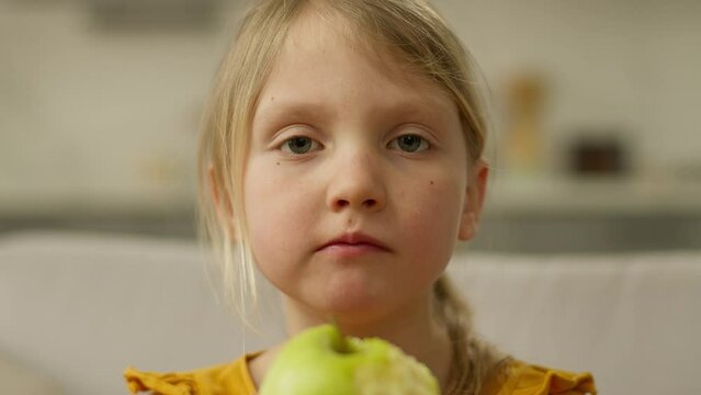 Close up little girl bite apple fruit chewing eating healthy food snack vitamin child daughter female kid offspring baby nourishment lunch childhood juicy hungry freshness diet face natural tasty home