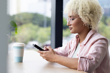 Young biracial woman using smartphone at work in business office