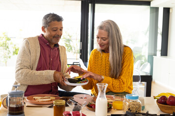 A biracial mature couple is enjoying breakfast together at home, at home