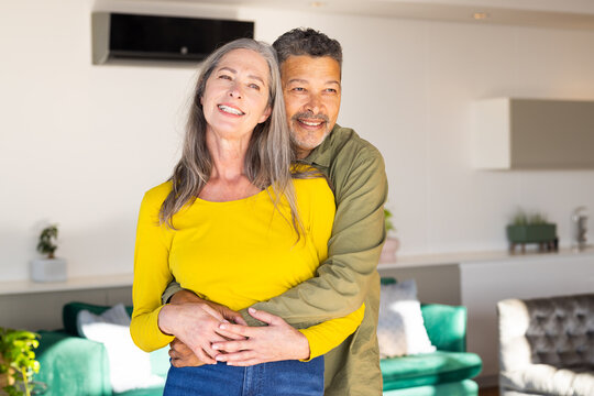 A mature biracial mature couple embracing and smiling warmly at home, at home