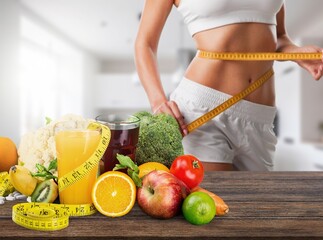 woman body measuring waist and vegetables on table.