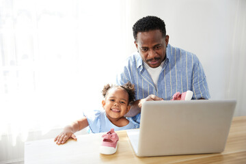Father doing online shopping and buying more shoes with daughter from laptop computer