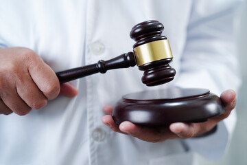 Asian doctor holding court hammer for and crime law justice, forensic medicine.