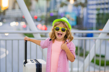 Excited tourist. Children travelling. Child boy going on summer trip, holding luggage travel bag outdoor.