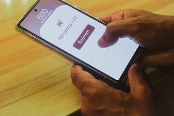 Man trying to redeem rewards points into cash on his mobile phone. Loyalty program for customer engagement in digital marketing concepts. Selective focus.