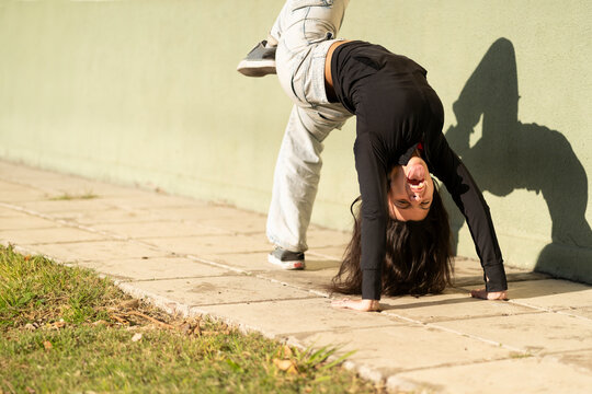 Teenage girl makes a bridge, bending her back in the street