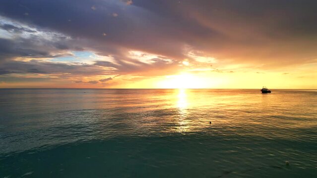 Gorgeous sunset on the Caribbean Sea with orange and red colors shining through heavy clouds in Jamaica. Tropical summer vacation and nature environment concept