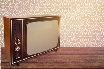 Old retro TV set on nightstand on background of wallpaper.