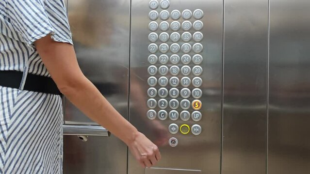Young woman presses a button in the elevator