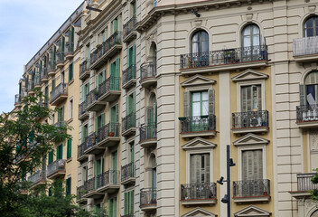 Naklejka premium Detail of vintage building architecture in Barcelona, Spain. Apartment building balconies with wrought iron railing and wooden shutters.