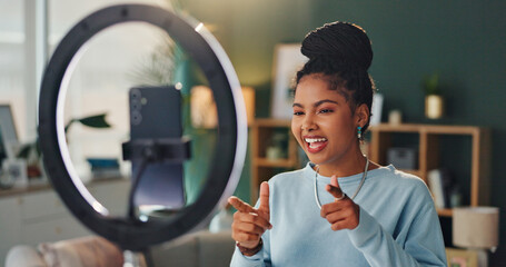 Woman, light and phone for vlogging in living room, smile and fingers for yes announcement. Online, female influencer and website at home with mobile, creative review for audience with media tech