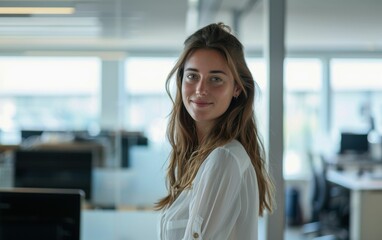 Fototapeta premium A woman with long brown hair and a white shirt is smiling in front of a window. Concept of happiness and positivity