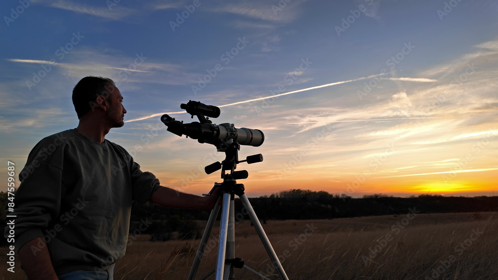 Wall mural amateur astronomer observing solar eclipse and sun with a telescope and special solar filter.